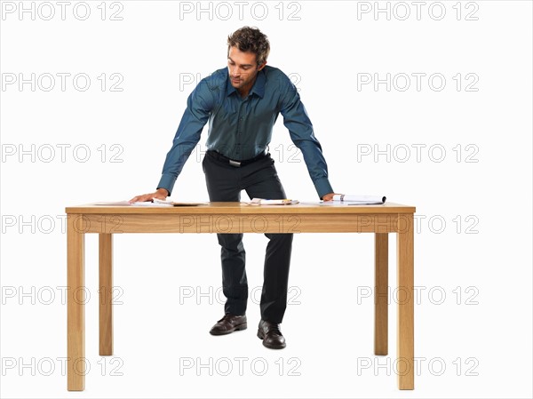 Portrait of smart business man standing with palms on table. Photo: momentimages