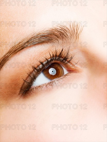 Studio shot of young woman, close-up of eye.