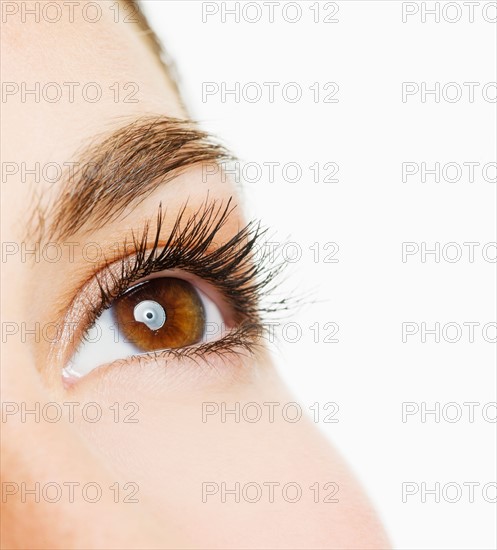 Studio shot of young woman, close-up of eye.