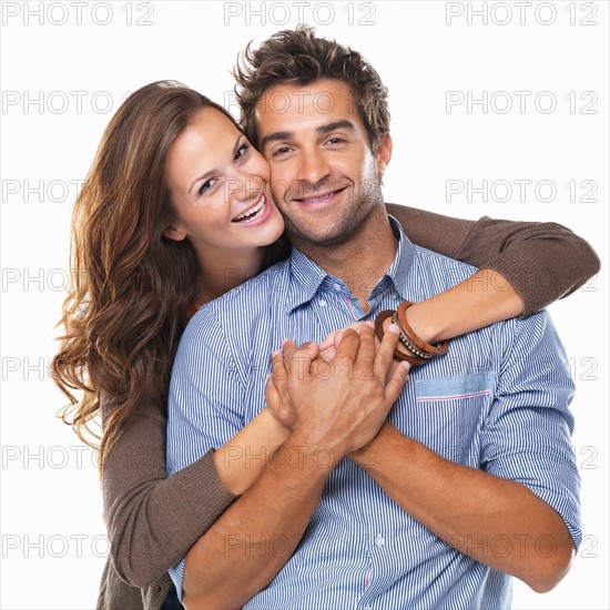Studio shot of young couple smiling and embracing. Photo : momentimages