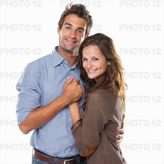 Studio shot of young couple embracing and holding hands. Photo: momentimages