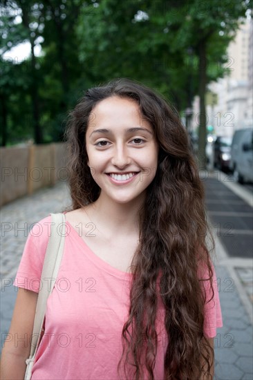 USA, New York, New York City, Portrait of smiling young woman standing on street. Photo : Winslow Productions