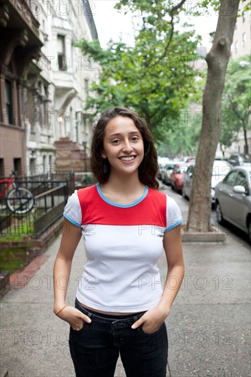 USA, New York, New York City, Portrait of smiling young woman standing on street. Photo: Winslow Productions