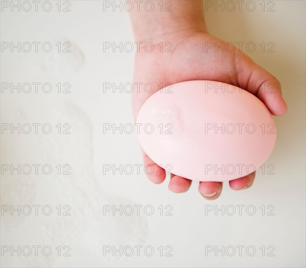 Close up of girl's (8-9) hand holding soap bar. Photo : Jamie Grill