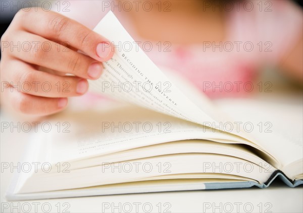 Close up of girl's (8-9) hand turning pages. Photo: Jamie Grill