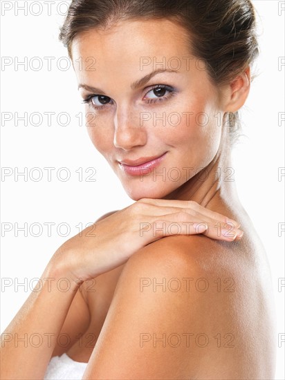 Studio shot of young attractive woman with hand on shoulder. Photo : momentimages