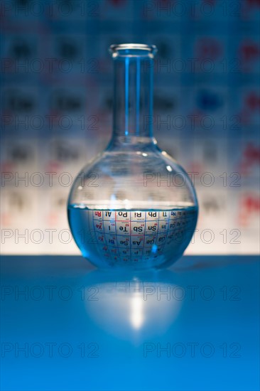 Beaker with periodic table in laboratory.