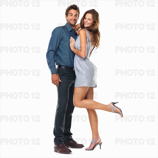 Studio shot of young couple standing together and smiling. Photo : momentimages