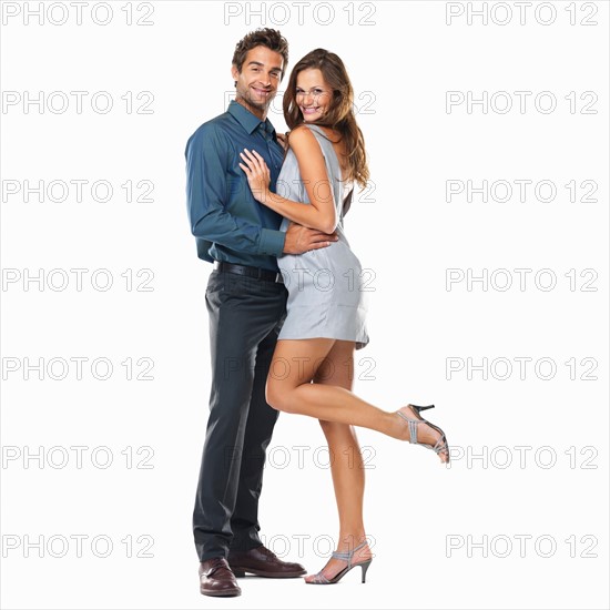 Studio shot of young couple standing together and smiling. Photo: momentimages