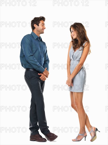 Studio shot of young shy man and woman standing face to face and smiling. Photo : momentimages