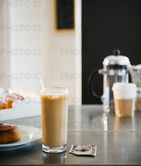 Close up of glass of iced coffee and money on table in coffee shop. Photo : Jamie Grill