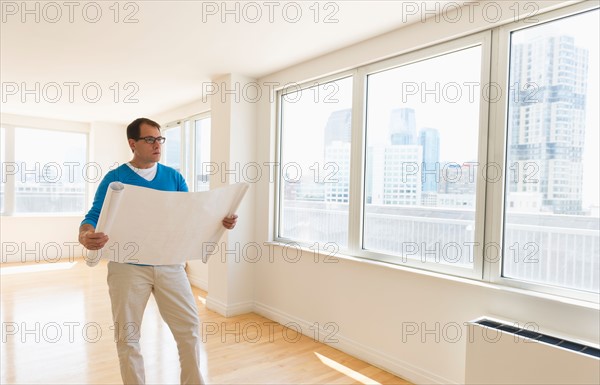 Architect reading blueprint in new office.