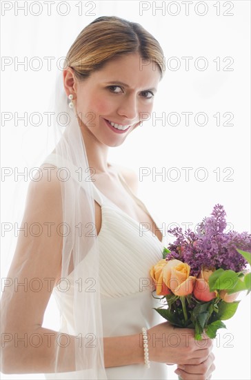 Studio portrait of bride holding floral bouquet.