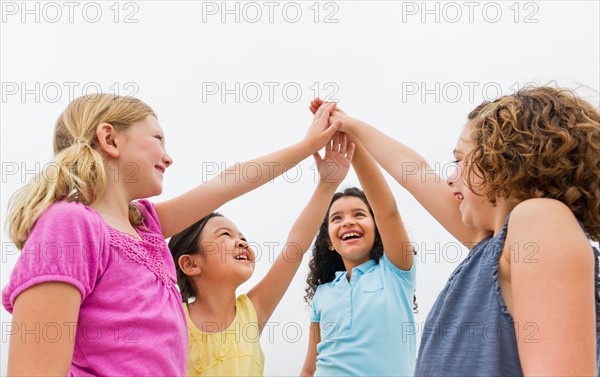 Girls (6-9) holding arms up in sky.