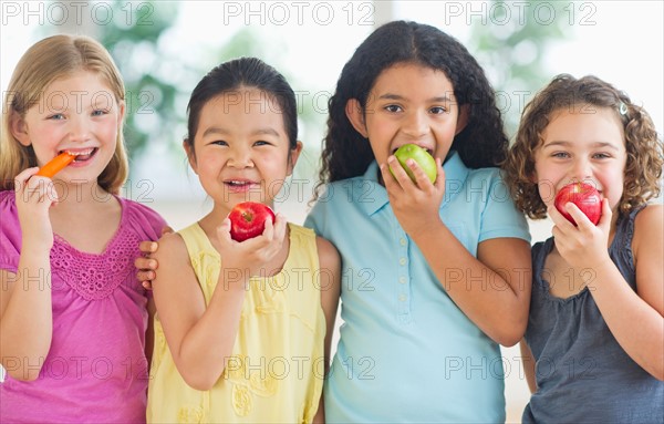 Portrait of girls (6-9) eating fruits.