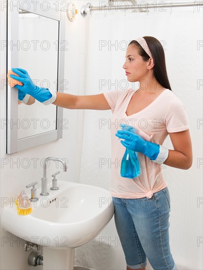 Young woman cleaning bathroom.