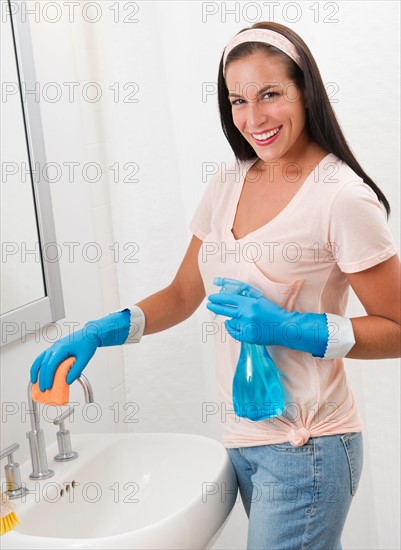 Young woman cleaning bathroom.