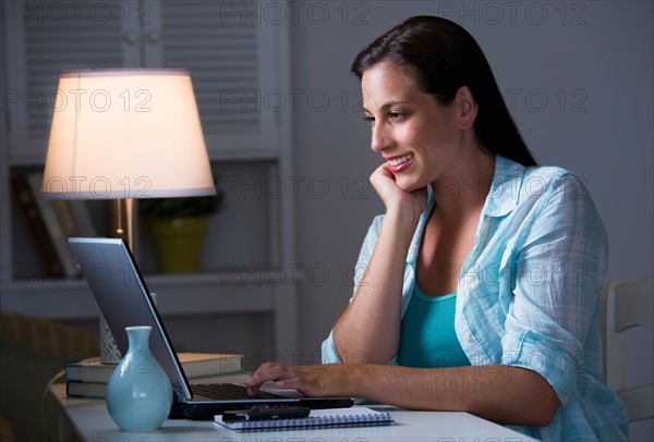 Woman using laptop at night.