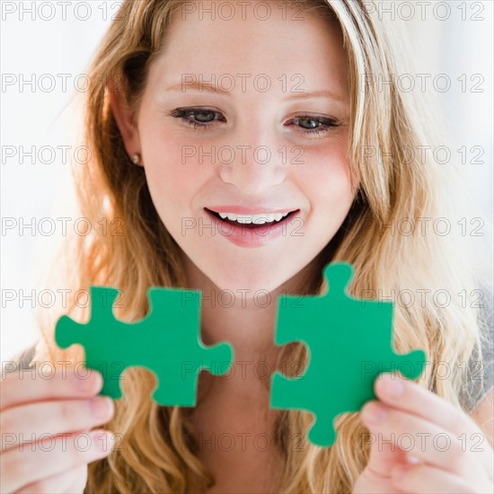 Young woman holding two green puzzles. Photo : Jamie Grill
