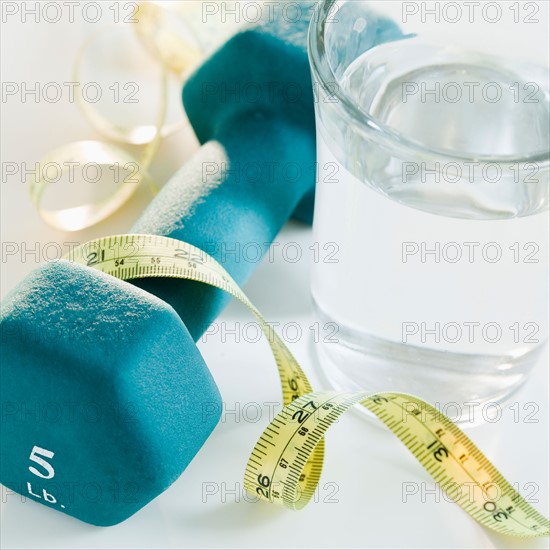 Tape measure, exercise weights and glass of water, studio shot. Photo : Jamie Grill