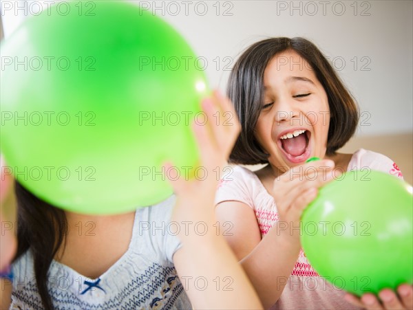 Close up of two girl's (8-9, 10-11) playing with green balloons. Photo: Jamie Grill