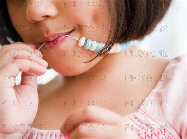 Close up of girl (8-9) with candy necklace. Photo : Jamie Grill