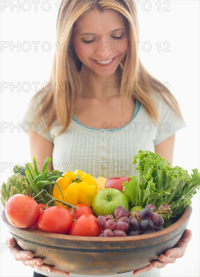Woman holding bowl of organic fruit and vegetables.