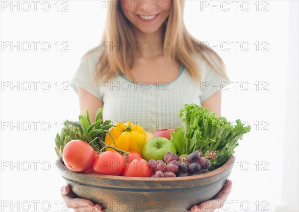 Woman holding bowl of organic fruit and vegetables.