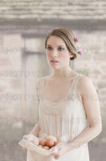 Ireland, Young woman carrying basket of eggs.