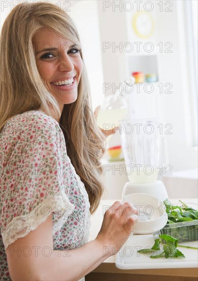 Smiling woman preparing drink. Photo : Jamie Grill