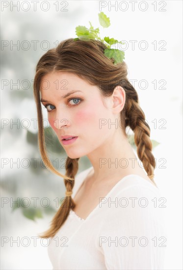 Studio portrait of young woman with leaves in hair.