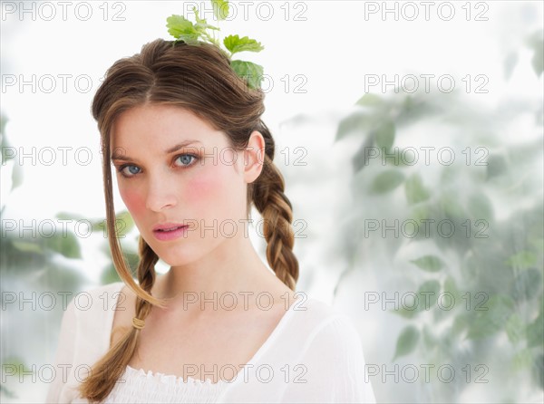 Studio portrait of young woman with leaves in hair.