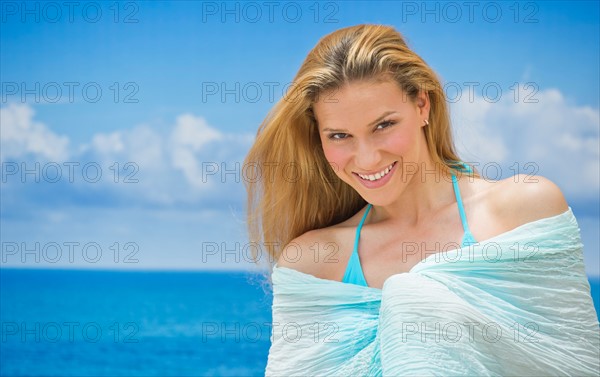 Woman wrapped in towel by sea.