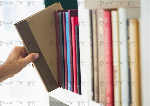 Hand choosing book from shelf.