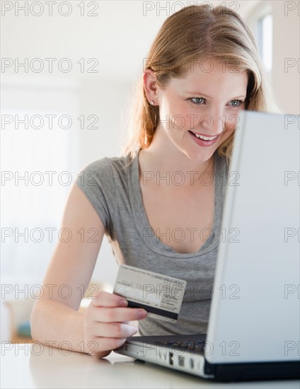 Young woman with laptop and credit card. Photo : Jamie Grill