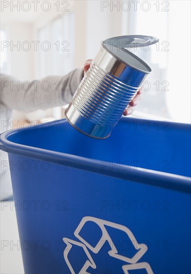 Woman putting metal can into blue recycling bin. Photo: Jamie Grill