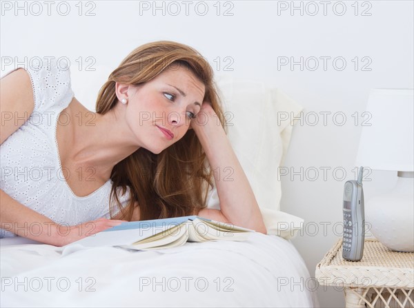 Portrait of young lying on bed and looking at phone. Photo: Daniel Grill