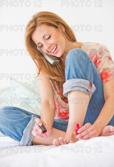 Portrait of young woman painting toe nails. Photo : Daniel Grill