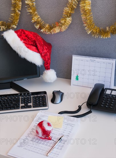 Close up of Santa hat and Christmas decorations on office desk. Photo : Daniel Grill