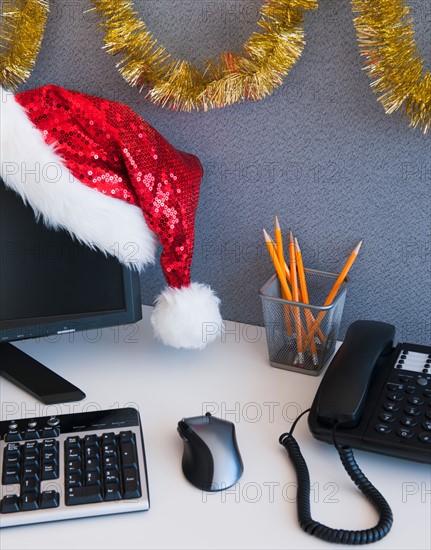 Close up of Santa hat and Christmas decorations on office desk. Photo : Daniel Grill