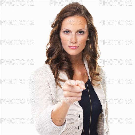 Studio shot of young woman pointing at camera. Photo : momentimages
