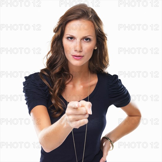 Studio shot of young woman pointing at camera. Photo : momentimages