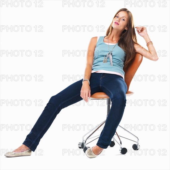 Confident woman sitting comfortably on chair against white background. Photo : momentimages