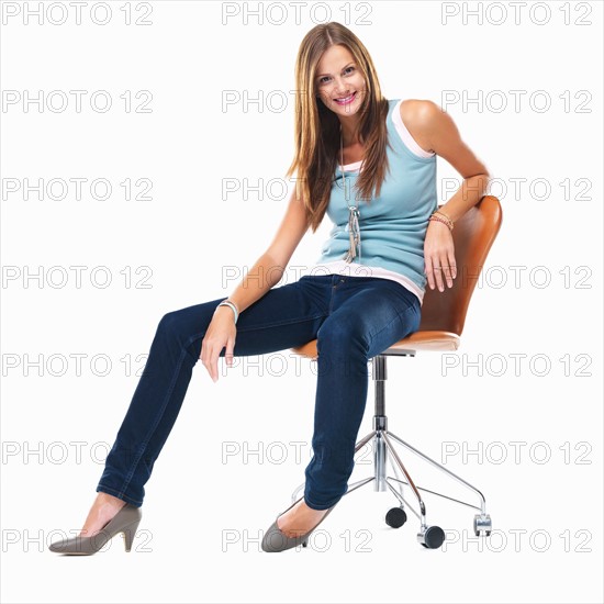 Attractive woman sitting on chair and smiling against white background. Photo : momentimages