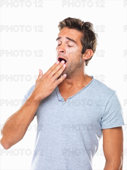 Studio portrait of young man yawning. Photo : momentimages
