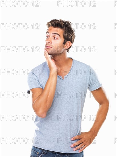 Studio shot of thoughtful young man with hand on chin. Photo : momentimages