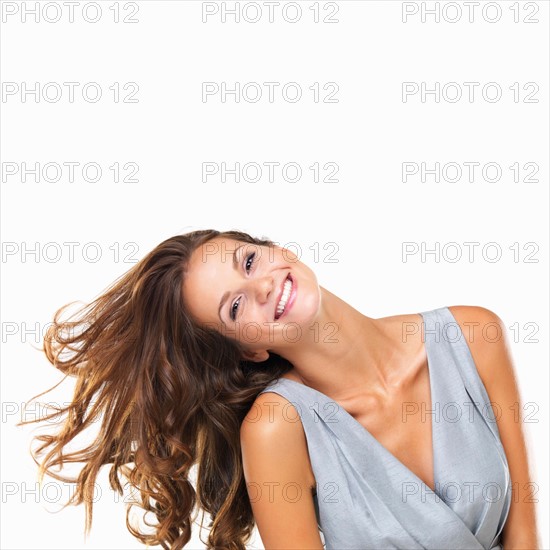 Studio portrait of young woman tilting her head and smiling. Photo: momentimages