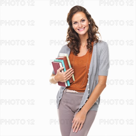 Studio portrait of attractive woman holding books and smiling. Photo : momentimages
