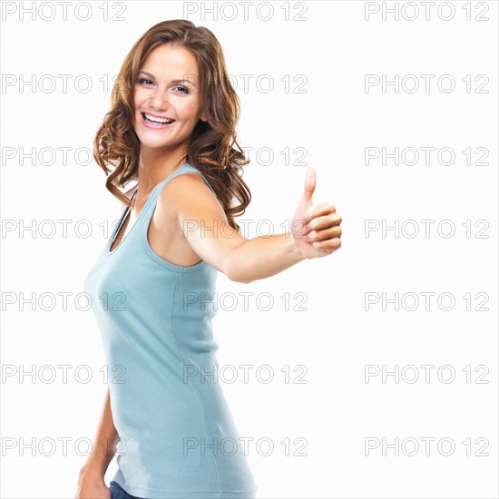 Studio portrait of attractive young woman with thumbs up. Photo : momentimages