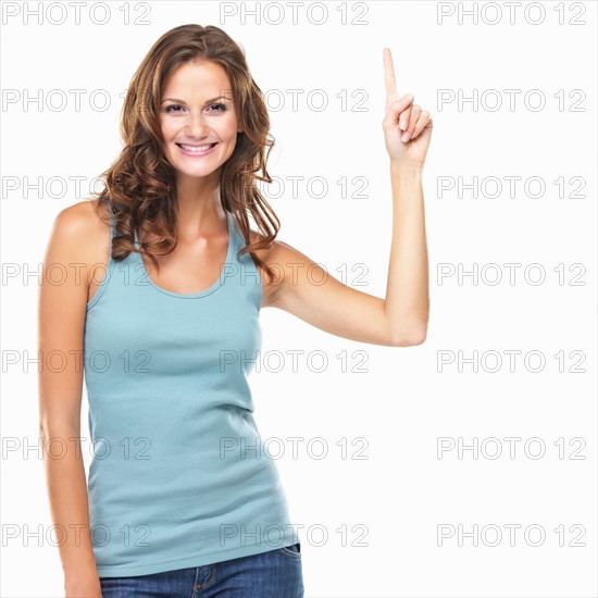 Studio portrait of attractive young woman pointing up. Photo : momentimages